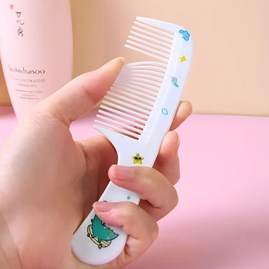 Peigne DemelJunior blanc avec motif dinosaure tenu en main