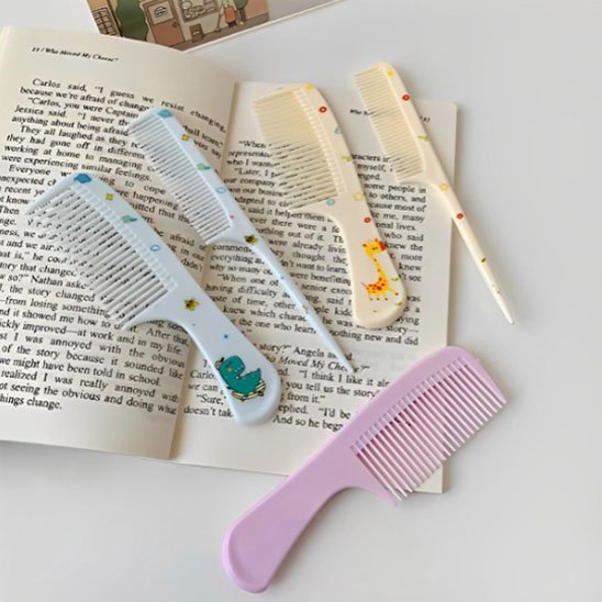 Peignes DemelJunior colorés avec motifs ludiques posés sur livre ouvert